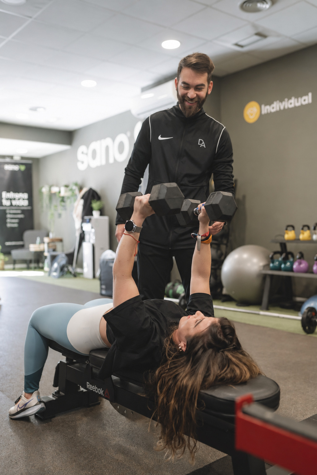 David asistiendo a una deportista durante un ejercicio de fuerza