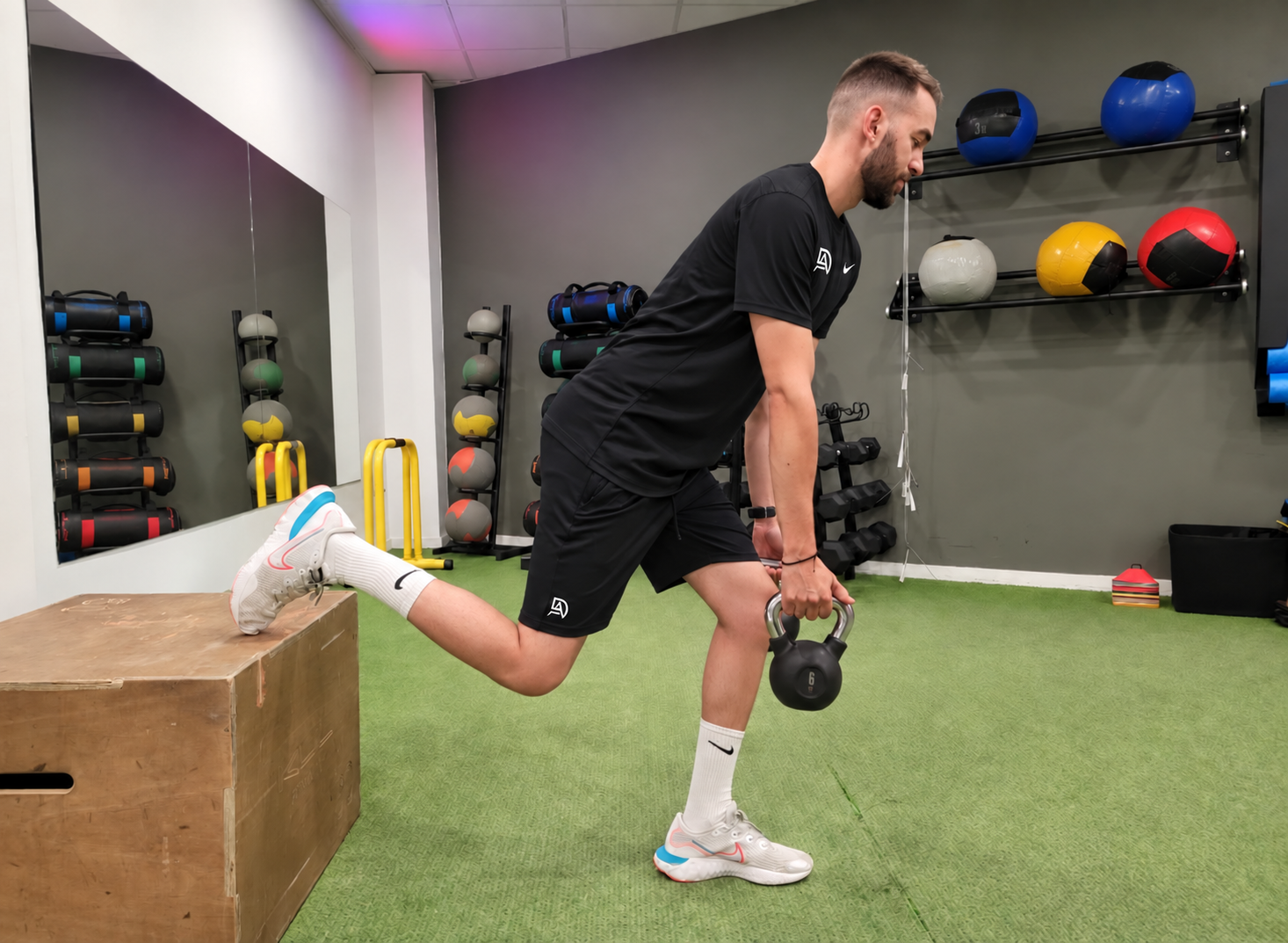 David realizando un ejercicio unilateral con kettlebell y camiseta negra, mostrado de cuerpo completo
