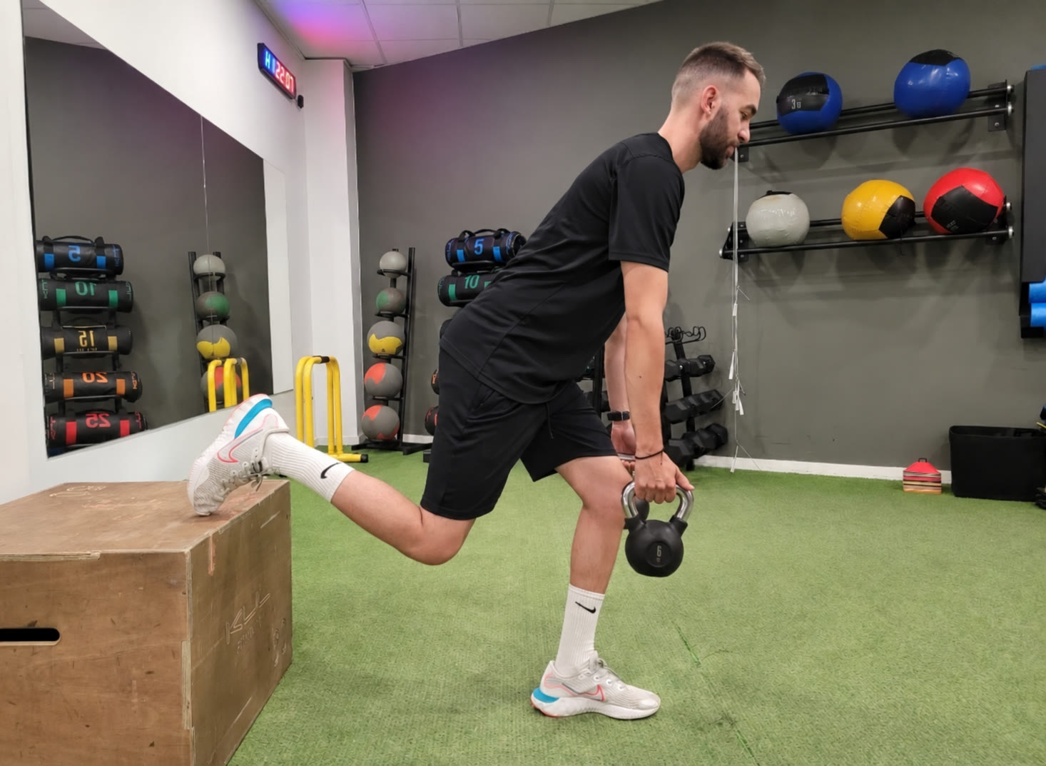 David realizando un ejercicio unilateral con kettlebell y camiseta negra, mostrado de cuerpo completo