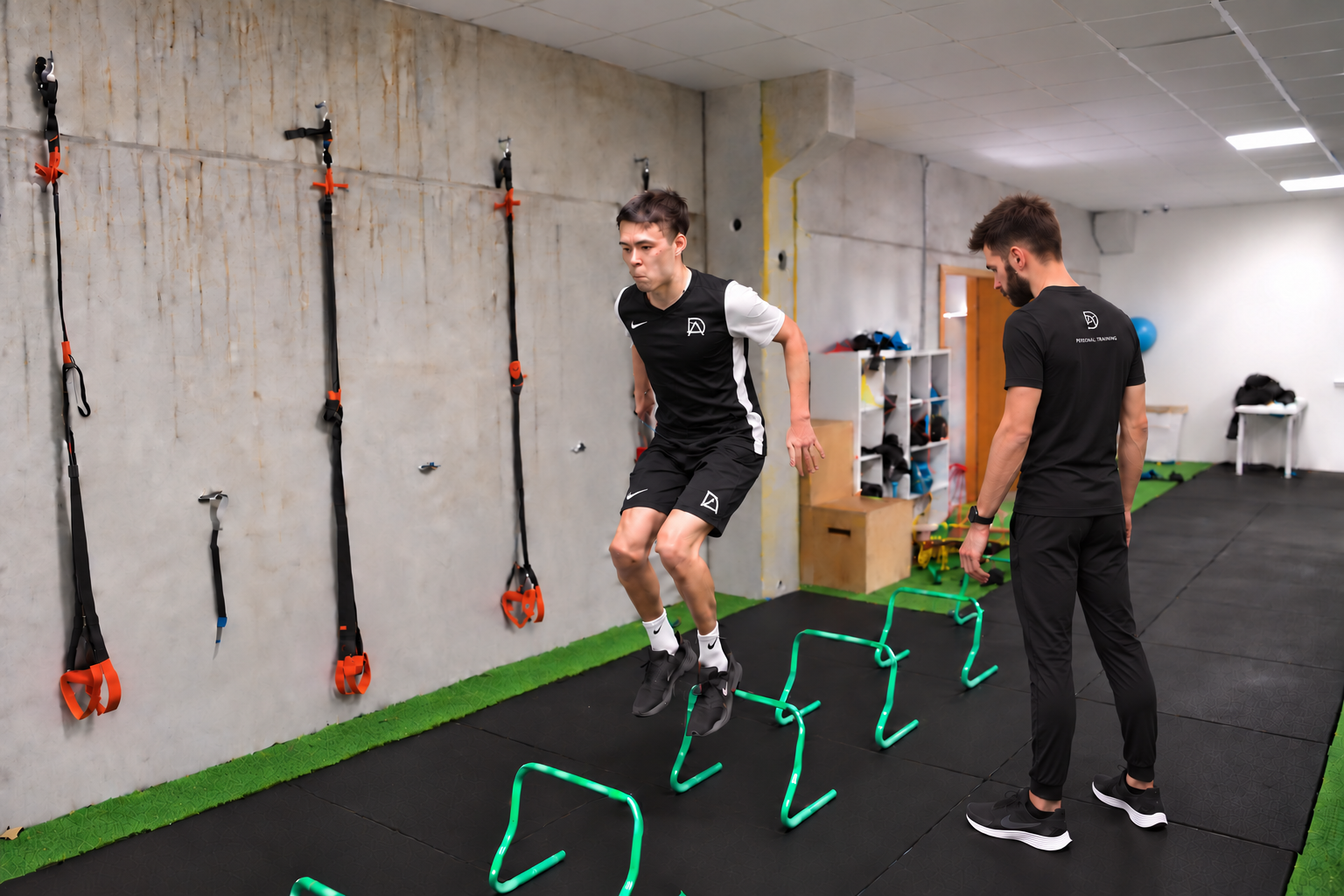 David Adanero de lado y de espaldas supervisando los pies de un futbolista durante los saltos sobre vallas